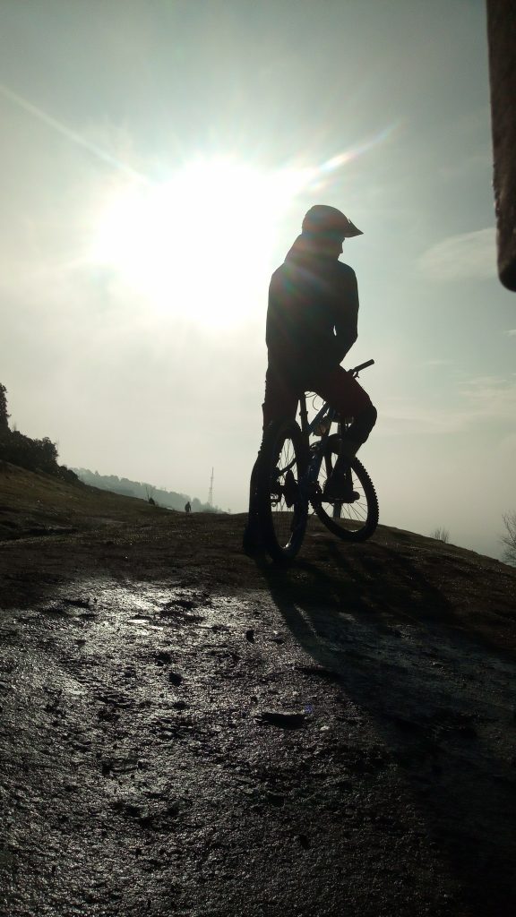Mountain bike riders silhouetted against the sun on top of a hill 